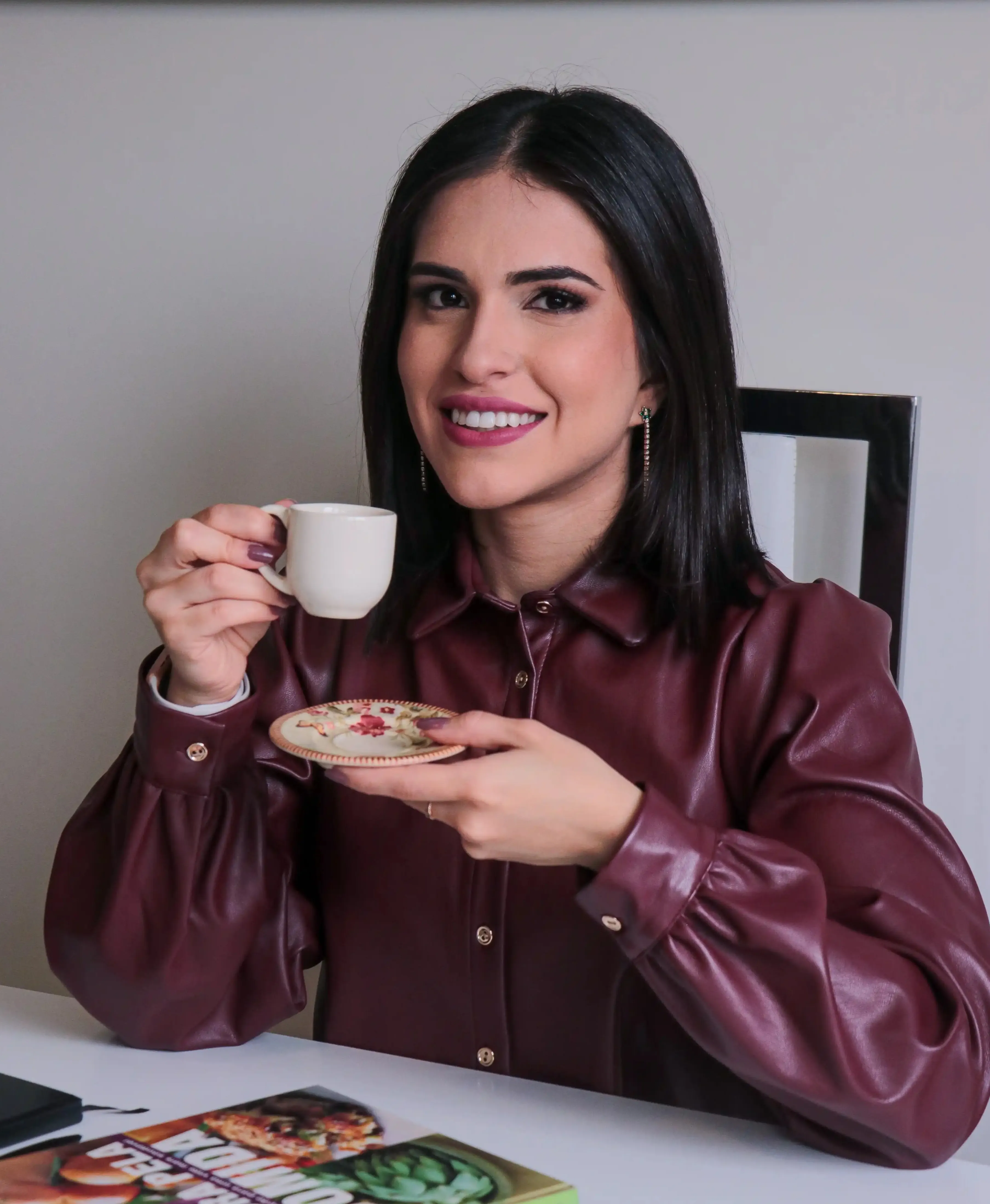 Priscila Oliveira à secretária, com um caderno aberto e uma caneta na mão.