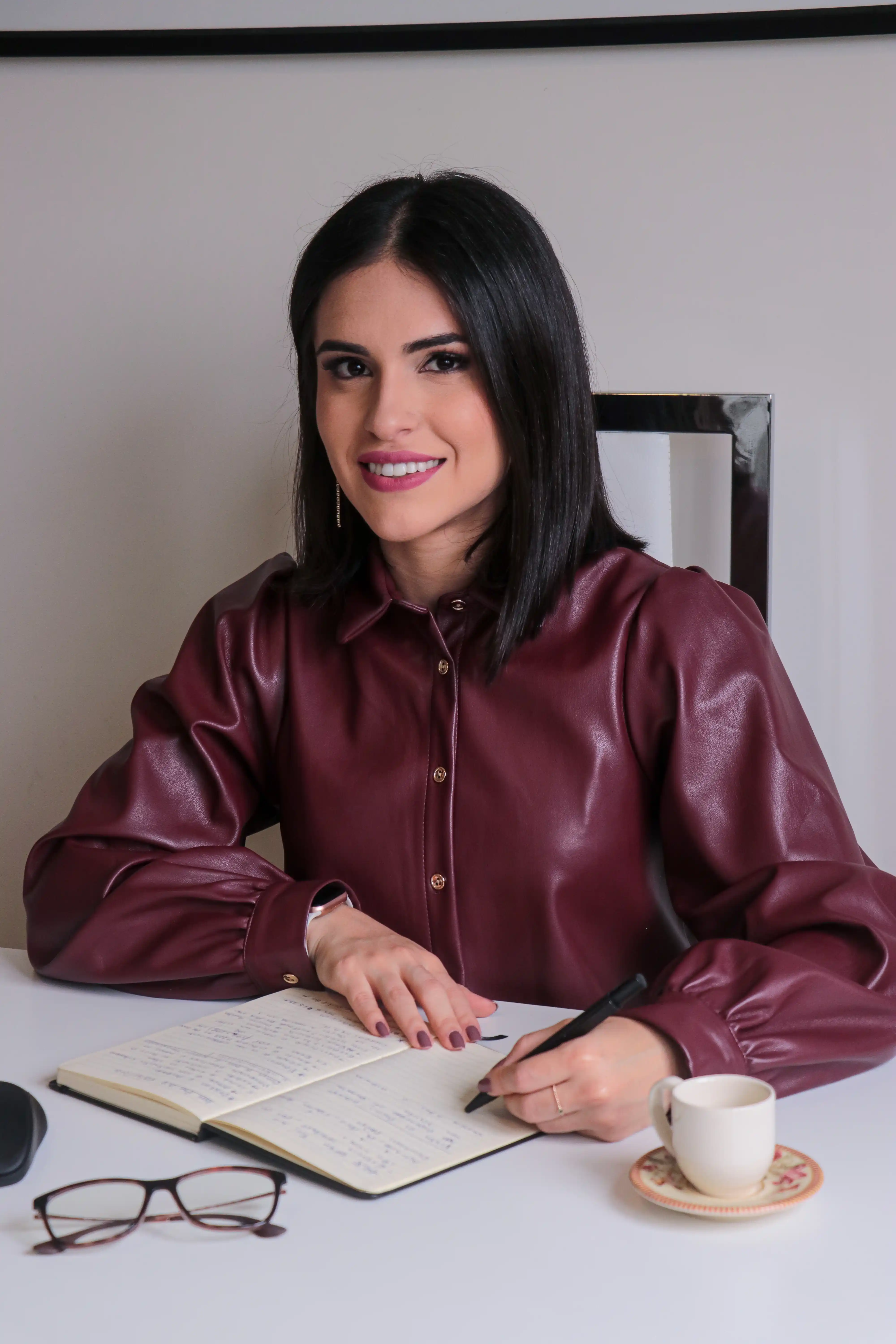 Priscila Oliveira sentada à secretária do consultório.